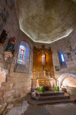Ortaçağ kilisesinin içinde dini heykeller, sunaklar ve vitray pencereler var.