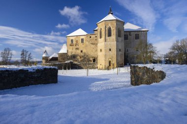Svihov Su Kalesi, parlak karla kaplı Gotik bir kale, açık bir kış gökyüzüne karşı duruyor.