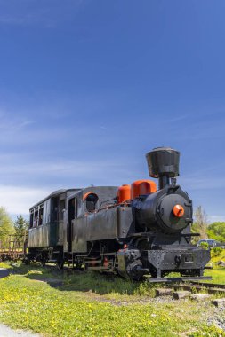 Eski model buhar treni açık mavi gökyüzünün altında duruyor.