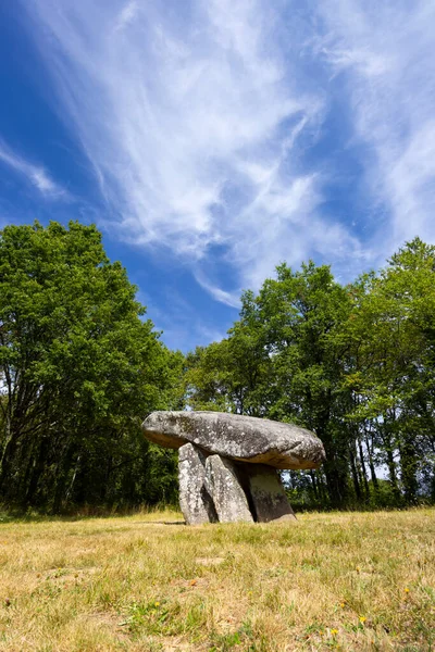 Megalitik dolmen yapısı mavi gökyüzünün altında çimenli bir alanda duruyor.