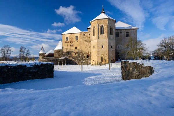 Svihov Su Kalesi, parlak karla kaplı Gotik bir kale, açık bir kış gökyüzüne karşı duruyor.