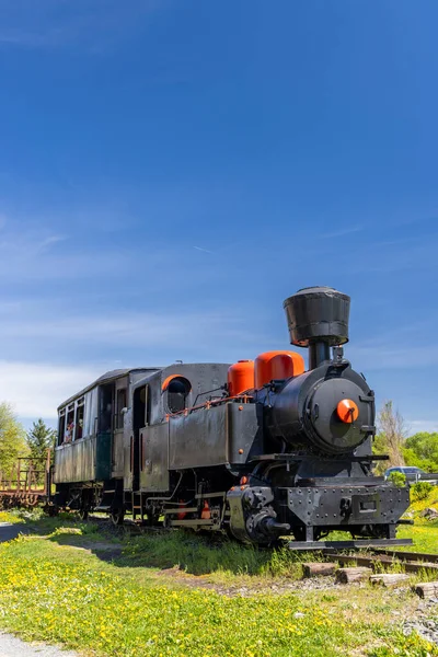 Eski model buhar treni açık mavi gökyüzünün altında duruyor.