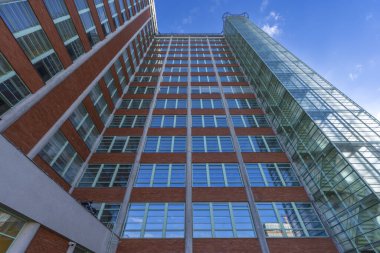 Camdan dış yüzeyi ve birçok penceresi olan yüksek katlı bir ofis binasının modern mimarisi