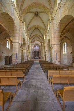 Boş sıralar, güneşli bir sunağa doğru uzanan tarihi bir manastır nave.