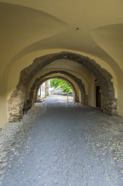 Tarihi manastır kemerleri kaldırım taşı ve çakıl zeminden manzaralı bir geçit oluşturuyor.