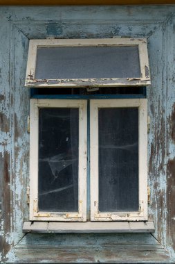 Dertli ahşap pencere, mavi boya çürümeyi ve kırsal dokuyu gösteriyor.