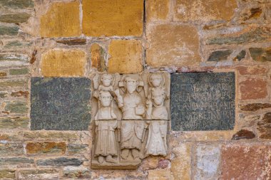 Antik bir manastır duvarına gömülmüş insan figürlerini ve dini sanatı gösteren tarihi bir taş oymacılığı.