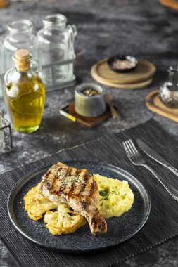 Patates püresi ve karnabaharla servis edilen domuz pirzolası, sağlıklı bir akşam yemeği için hazır.