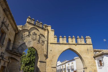 Mimari detaylar ve açık mavi gökyüzünün altındaki armalarla tarihi taş kemer yolu cephesi