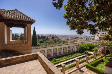 Mavi gökyüzü altındaki tarihi Fas mimarisi ve huzur bahçelerinin panoramik manzarası, Granada