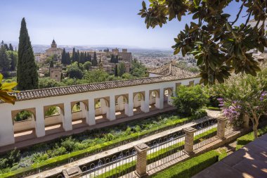 Generalife Bahçeleri, uzaktaki Alhambra sarayı ile antik mimari ve çeşmeleri gösteriyor.