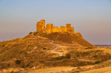 Antik şato, sıcak bir İspanyol gün batımında kuru bir tepenin üzerinde gururla duruyor.