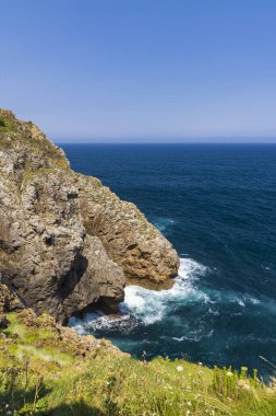 Dik uçurumlar ve Cantabrian Denizi 'nin berrak mavi suları Parlak yaz gökyüzünün altında