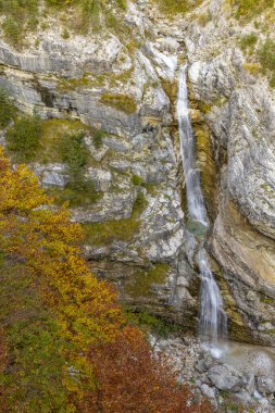 Şelale sonbahar sezonunda kayalık dağ uçurumlarından aşağı düşüyor, Bovec, Slovenya