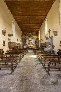 Mortemart kilisesi sıraları, taş zemini, ahşap tavanı ve dekore edilmiş sunağı gösteriyor.