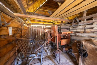 Slovakya 'nın Ruzomberok kentindeki eski bir kırsal ahır içinde eski ahşap tarım makineleri ve el arabası.