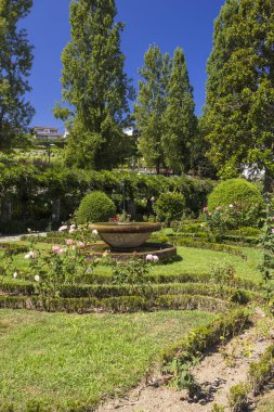 Taş çeşme Portekiz 'deki bir park bahçesinde çitlerle ve çiçeklerle bir odak noktası oluşturuyor.