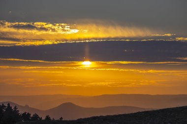 Güneş ışığı bulutları delip geçiyor. Yuvarlanan tepelerin üzerinde. Güzel akşam alacakaranlığı boyunca.