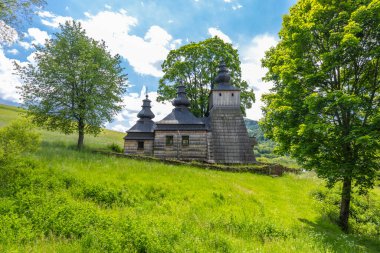 Ahşap Yunan Katolik Kilisesi Ağaçlı, mavi gökyüzü yeşil bir tepenin üzerinde