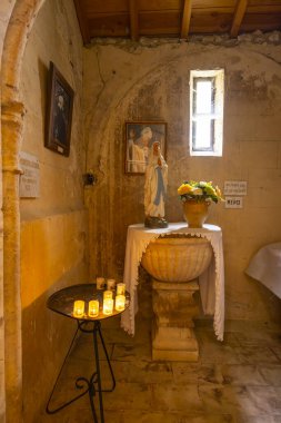 İçi Meryem Ana heykelini, mumları ve dini resimleri mütevazı bir kilisede gösteriyor.