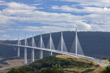Viaduc de Millau, a cable stayed bridge, carrying vehicles across a green valley under a blue sky