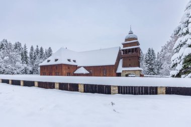 Tarihsel ahşap eklem kilisesi kışın karla kaplı, her yer yeşil ormanla çevrili.