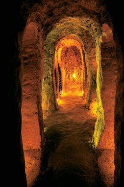 Yeraltı tüneli loş bir şekilde aydınlandı ve antik taşların arasında gizemli bir yol yarattı.