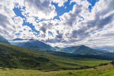 Yeşil Pireneler dağlar ve tepeler dramatik bulutlu bir gökyüzü altında güneş ışınları altında parlıyor