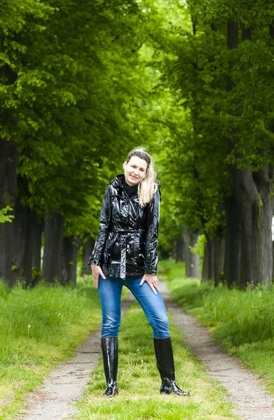 Woman wearing rubber boots in spring alley — Stock Photo, Image