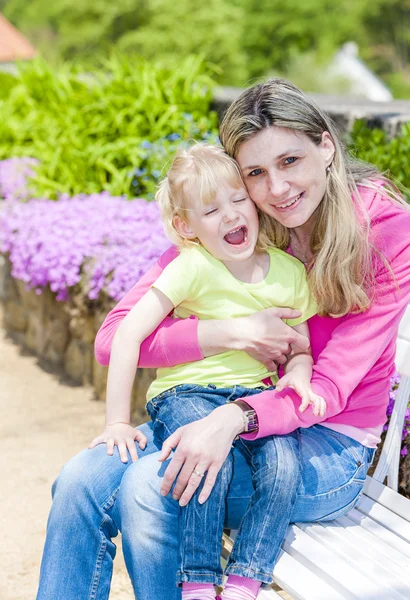 Madre con su hija sentada en el jardín de primavera —  Fotos de Stock