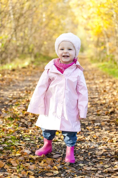 Liten flicka klädd i gummi stövlar i höstliga naturen — Stockfoto