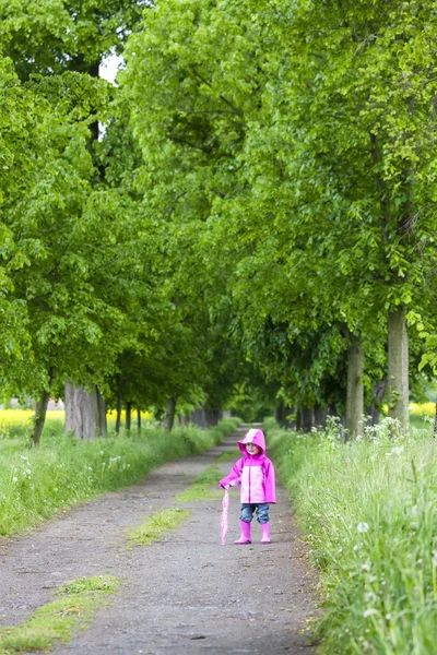 Liten flicka klädd i gummi stövlar med ubrella i våren gränd — Stockfoto