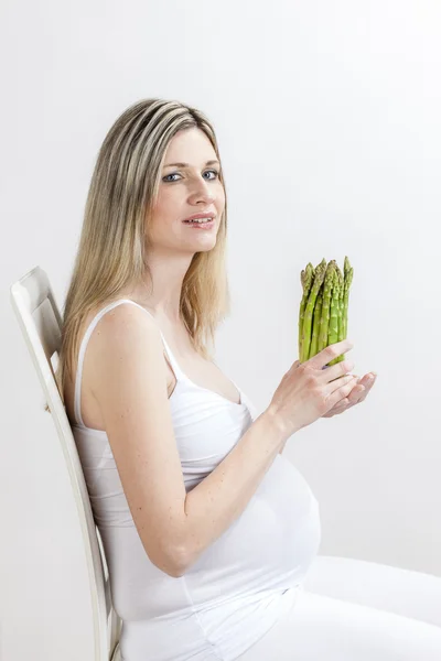 Беременная женщина держит зеленую спаржу — стоковое фото