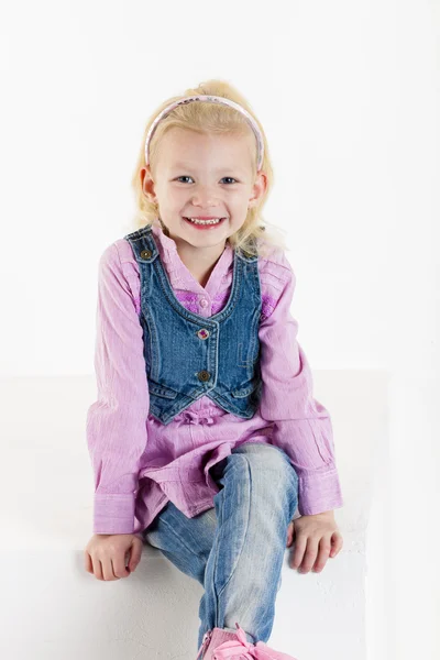 Sitting little girl wearing jeans — Stock Photo, Image