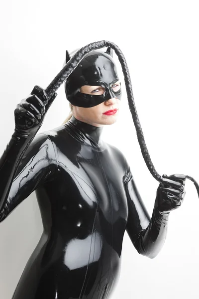 Standing woman wearing latex clothes with a whip — Stock Photo, Image