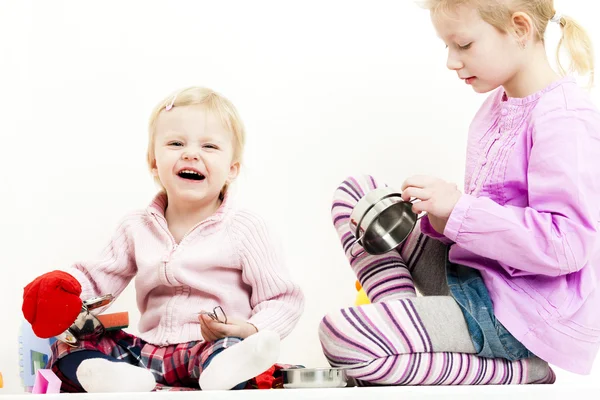 Two little girls playing with child dish — Stock Photo, Image