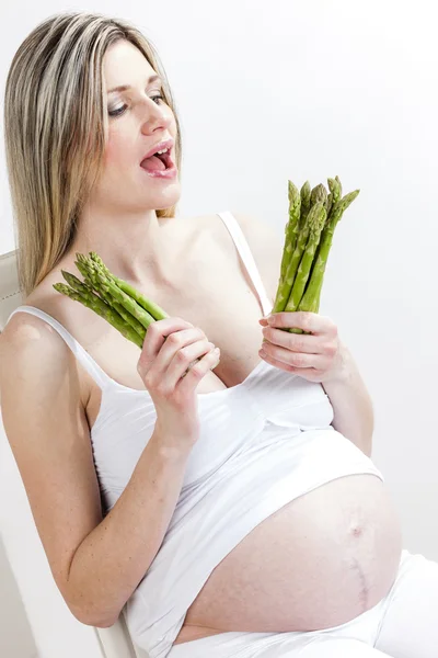 Mulher grávida segurando espargos verdes — Fotografia de Stock