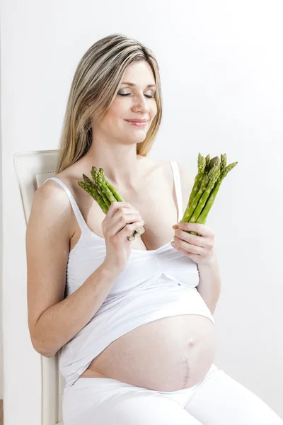 Pregnant woman holding green asparagus — Stock Photo, Image