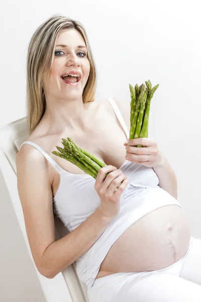 Mulher grávida segurando espargos verdes — Fotografia de Stock