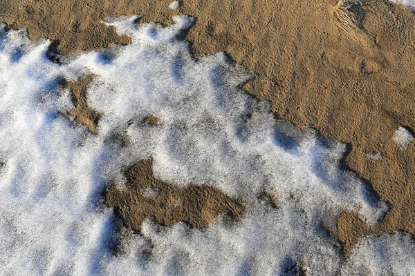 Nieve derretida sobre suelo arenoso —  Fotos de Stock