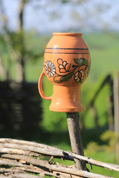 Clay jug on wooden fence in sunny day — Stock Photo, Image