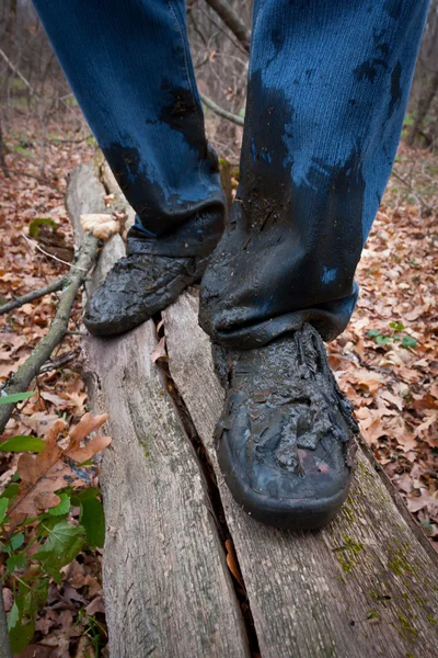 Botas hombres en la suciedad en un tronco en el bosque — Foto de Stock