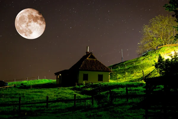 ukrainian house in village under night sky and big moon
