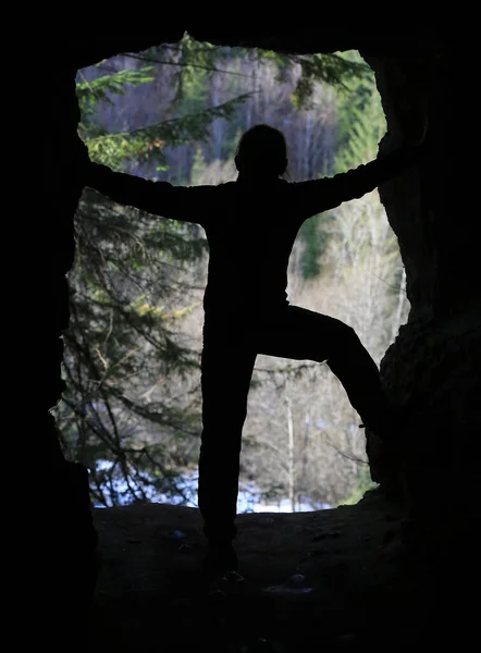 Silhouettes of a young man in a cave in the forest