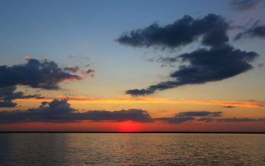 Gölün yüzeyinde akşam gökyüzü olan dramatik gün batımı manzarası.