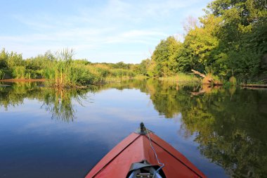 Kırmızı kano yazın mavi nehir suyunda yüzer.