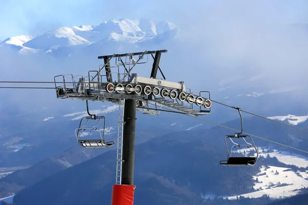 Chairlift na estação de esqui de inverno contra o fundo da montanha — Fotografia de Stock