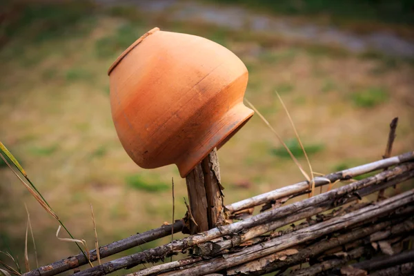 Clay jug on wooden fence — Stock Photo, Image