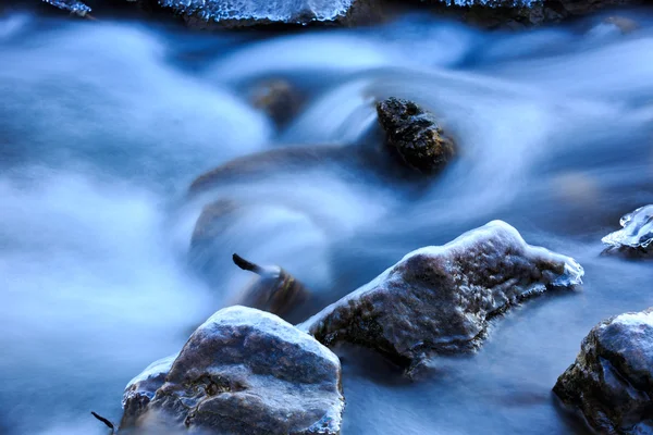 Bevroren stenen in het water van de beek — Stockfoto