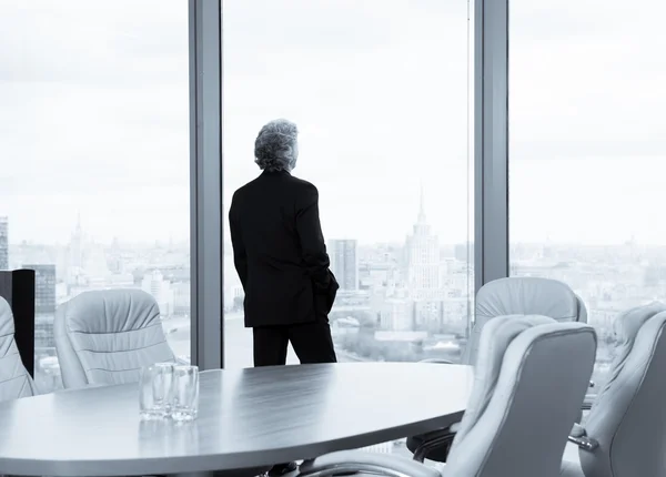 Geschäftsmann mittleren Alters schaut aus dem Fenster — Stockfoto